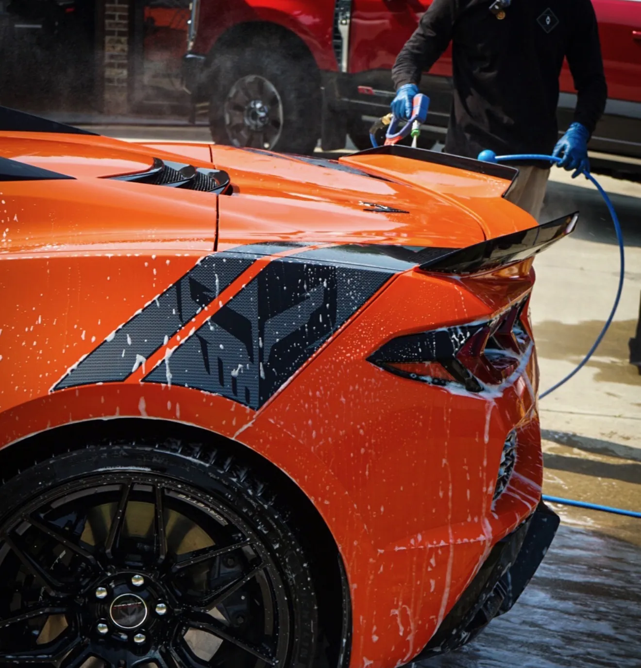 Mobile ceramic coating near Binghamton, NY: the Auto Aesthetics crew working on an orange Corvette in a customer driveway