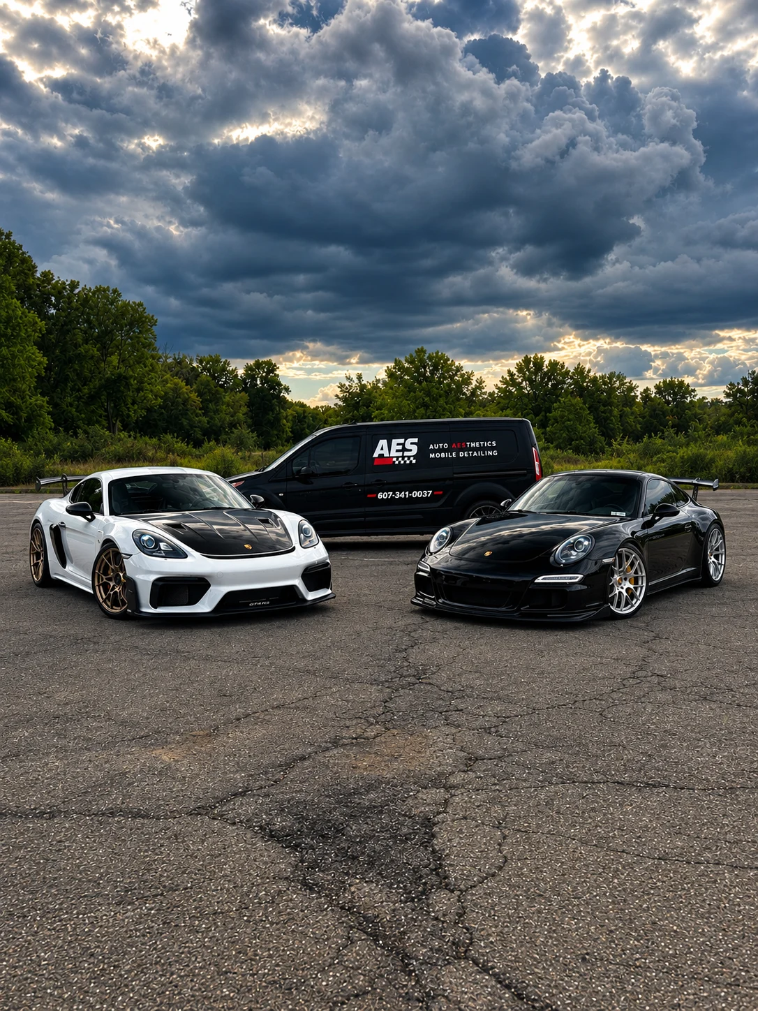 Two Porsche sports cars parked in front of the Auto Aesthetics mobile detailing van
