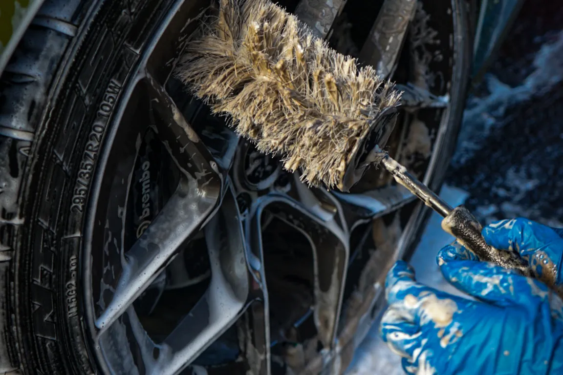 Hands scrubbing a wheel barrel by hand during a car detailing job in Binghamton, NY, one of the spots most detailers skip